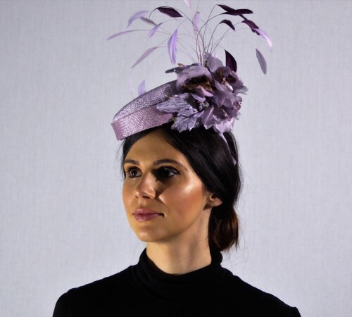 Bell boy style fascinator in lilac with matching flower and feathers.