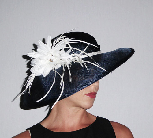 An unusual dropped brim to one side with shallow crown. Shown here in Navy Sinamay with White trim. Large flower & Biot Feathers.