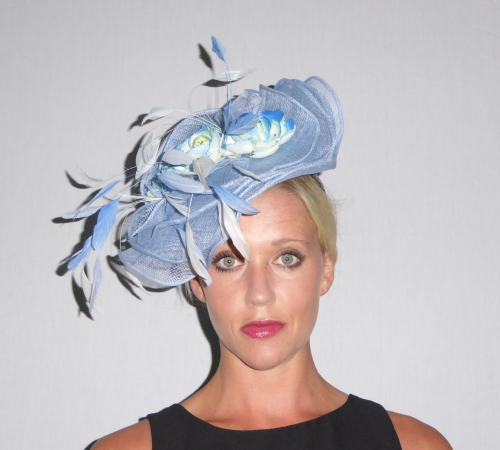 Free form Sinamay take on a wave effect on this layered Hatinator. Set on a headband and decorated with blue/white feathers and flowers.