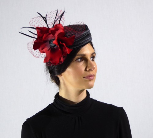 Pill box style  cocktail hat in black satin with red veiling and black biot feathers.